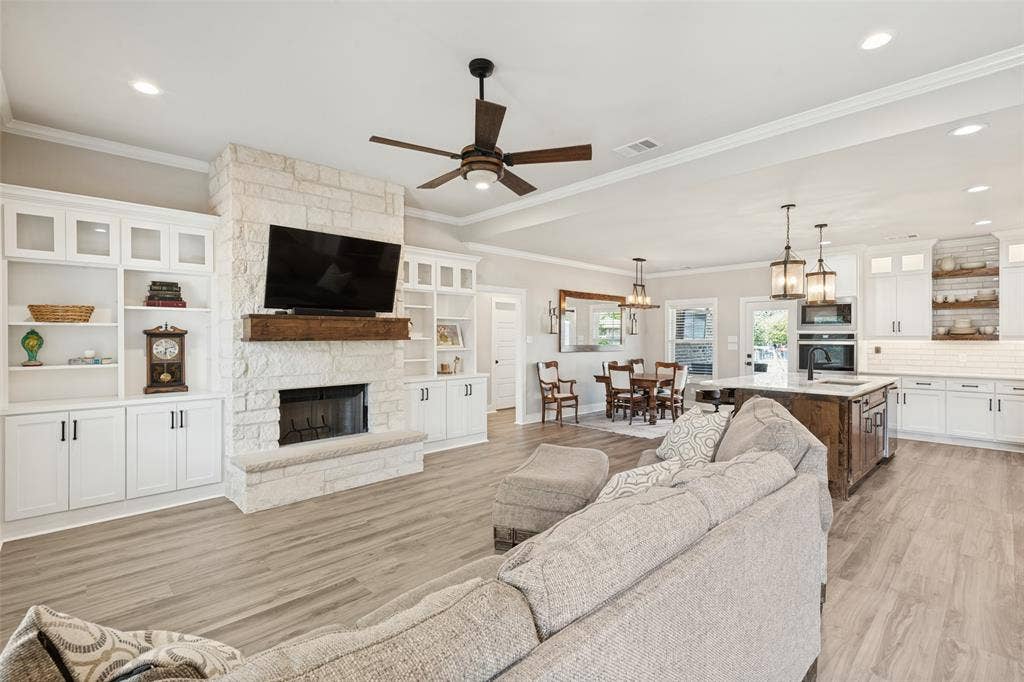 108 Rye Place, Gun Barrel City, TX 75156 Open-concept living space featuring wood-finish flooring, a stone-faced fireplace with a wood mantle, and built-in white cabinetry