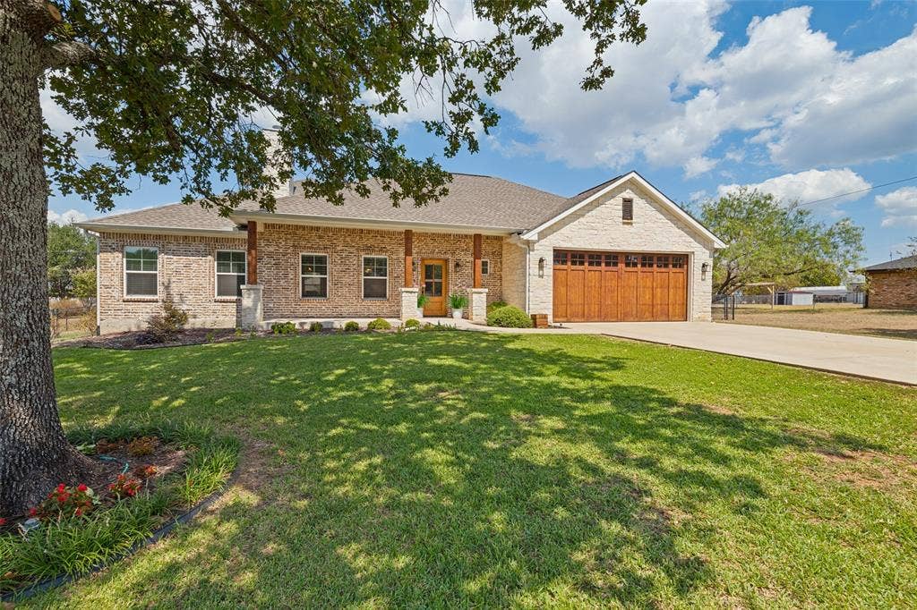 108 Rye Place, Gun Barrel City, TX 75156 Brick exterior with stone accents, wood-finish garage door, covered front porch with wood columns, and a concrete driveway