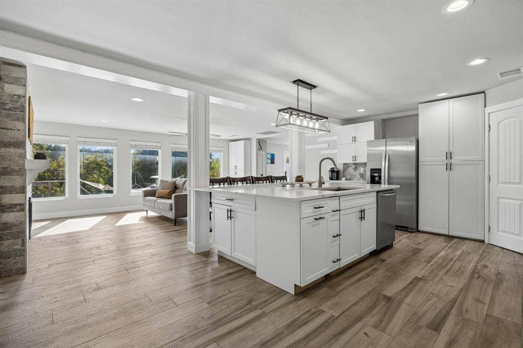 The quartz counters, stainless steal appliances, stunning lighting levels up this kitchen.