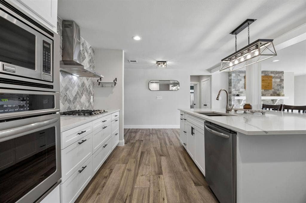 The quartz counters, stainless steal appliances, stunning lighting levels up this kitchen.