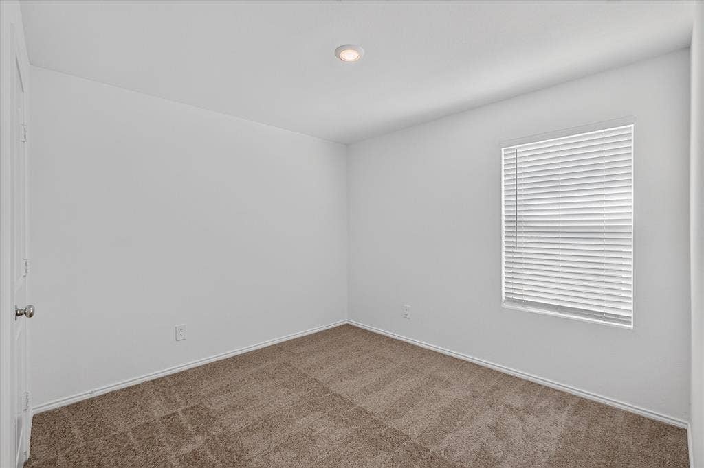 Recessed ceiling lighting, neutral carpet flooring, white walls, and a window with blinds