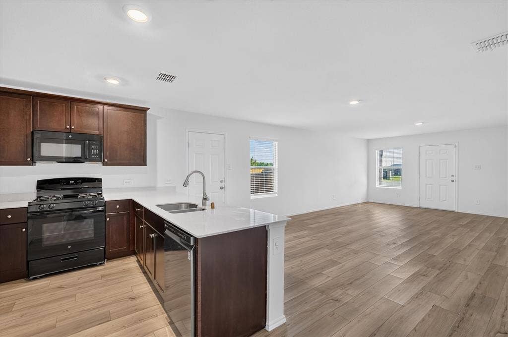 Open-concept living space with wood-finish flooring, recessed lighting, and white walls