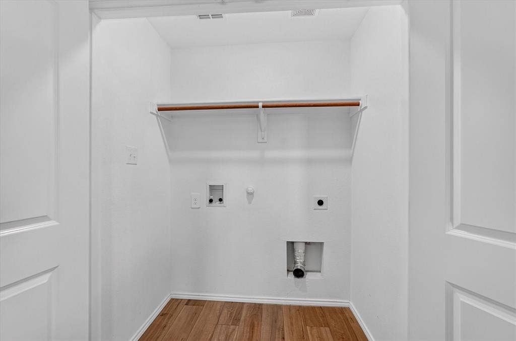 Dedicated laundry area featuring wood-finish flooring, a built-in shelf, and a clothing rod