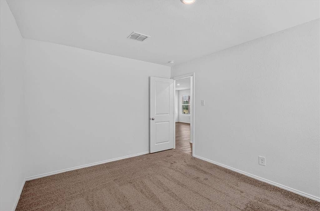 Carpeted room with white walls, a white door, and a flush-mount ceiling light