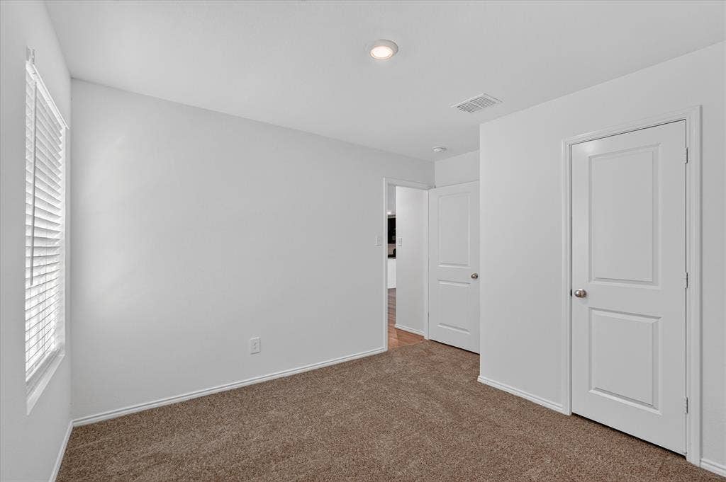 Carpeted room featuring a white interior door, a window with horizontal blinds, and a recessed ceiling light