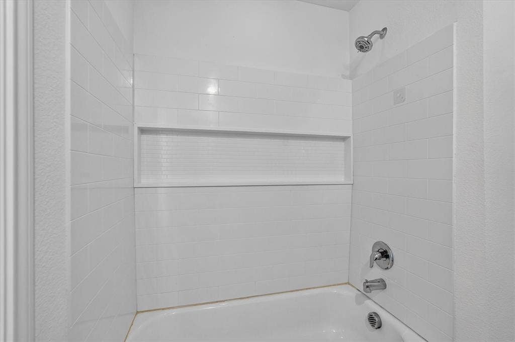 White subway tile shower surround with an integrated niche, chrome fixtures, and a white tub
