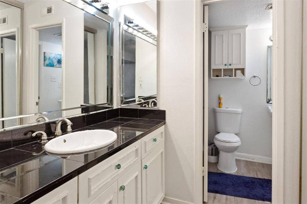 13026 Leader Street, #951, Houston, TX 77072 Bathroom 1 - Vanity with a white oval sink, chrome faucet, and dark tiled countertop
