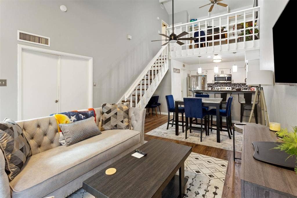 13026 Leader Street, #951, Houston, TX 77072 Vaulted ceiling living area with wood-finish flooring, staircase with white railings, and a loft overhead