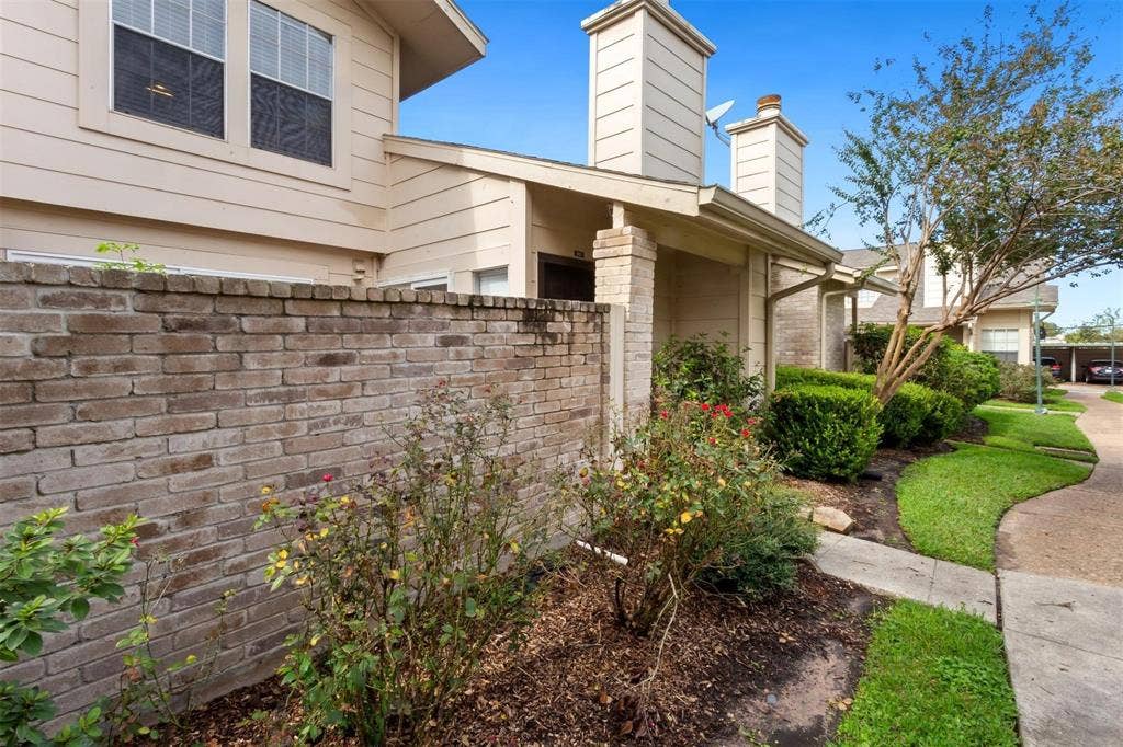 13026 Leader Street, #951, Houston, TX 77072 Brick fence with integrated landscaping, mature shrubs, and manicured lawn