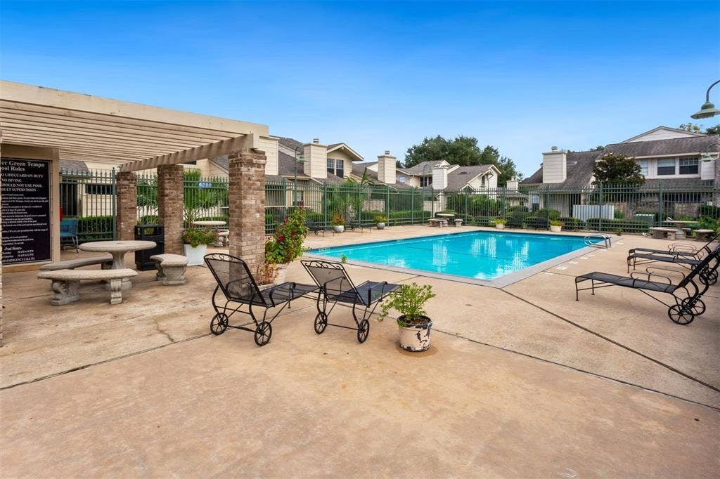 13026 Leader Street, #951, Houston, TX 77072 Community swimming pool with a surrounding concrete deck, shaded pergola with brick columns, and a perimeter fence