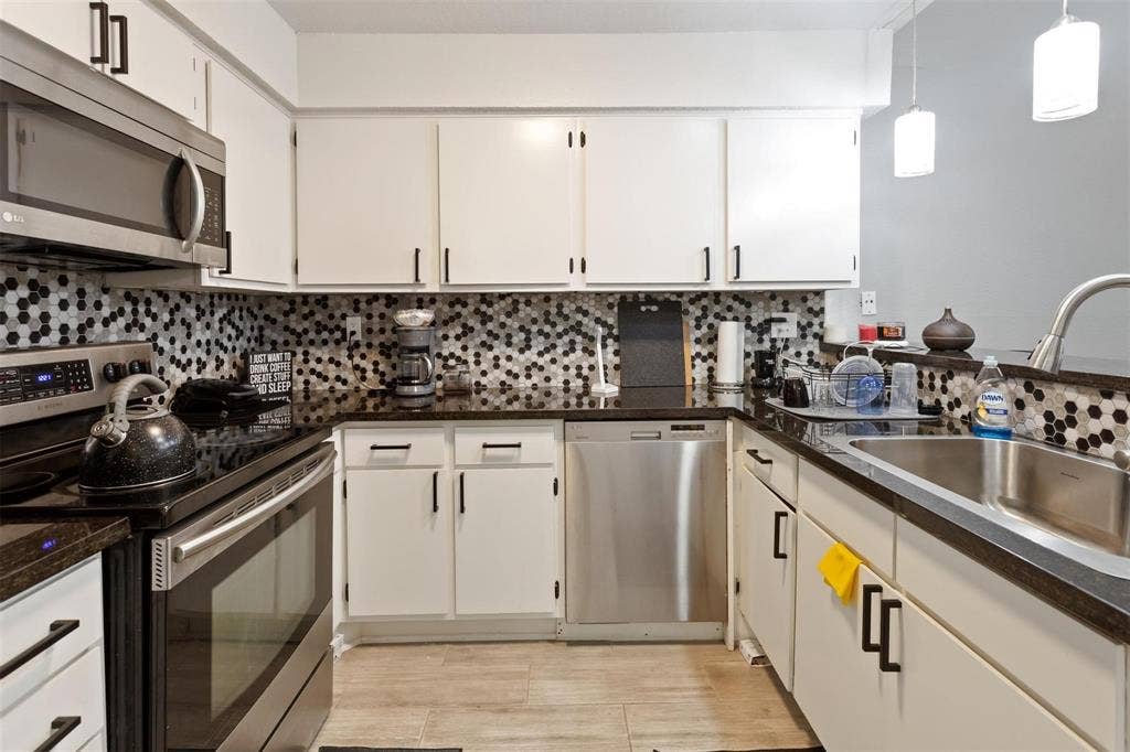 13026 Leader Street, #951, Houston, TX 77072 Kitchen featuring white cabinetry, dark countertops, a tiled backsplash, stainless steel appliances, and wood-finish flooring