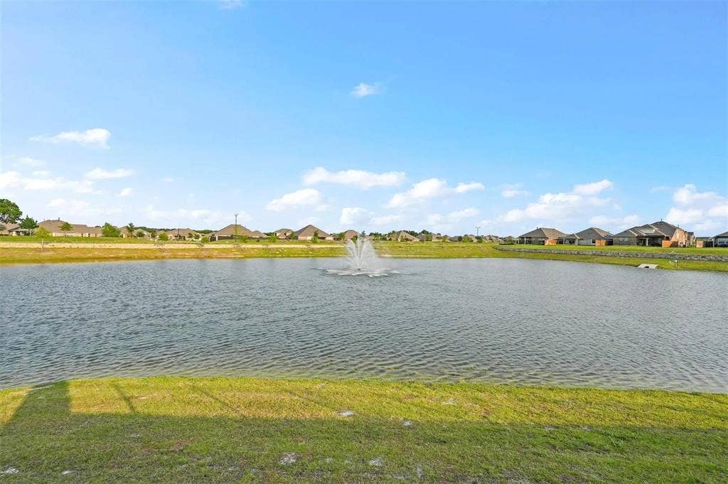 602 Brock Drive, Anna, TX 75409 Waterfront property featuring a pond with an active fountain and a grassy bank