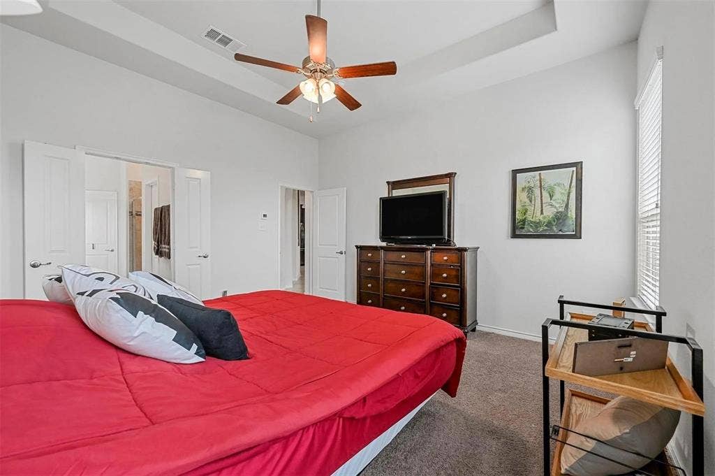 602 Brock Drive, Anna, TX 75409 Tray ceiling with a ceiling fan, white paneled doors, and a window with blinds