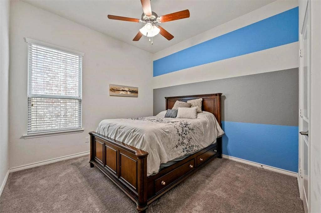 602 Brock Drive, Anna, TX 75409 Carpeted room featuring a ceiling fan, window with blinds, and a wall with horizontal blue and gray stripes