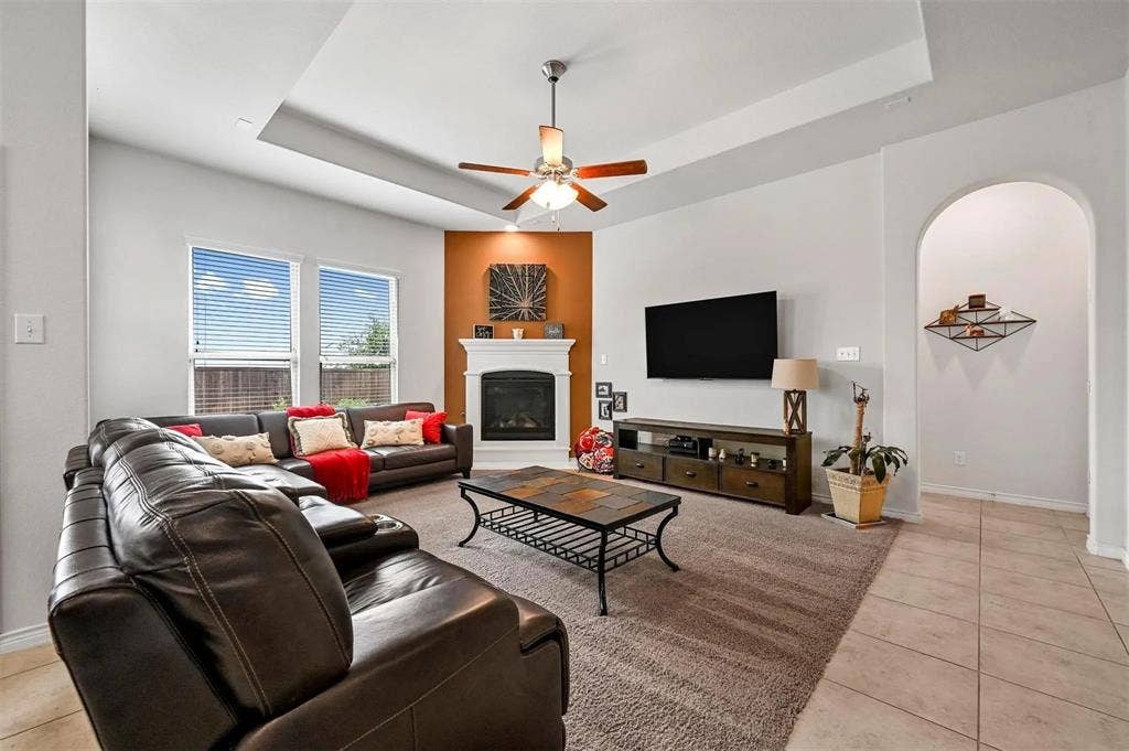 602 Brock Drive, Anna, TX 75409 Living area featuring a tray ceiling, ceiling fan, and a built-in fireplace with white mantel