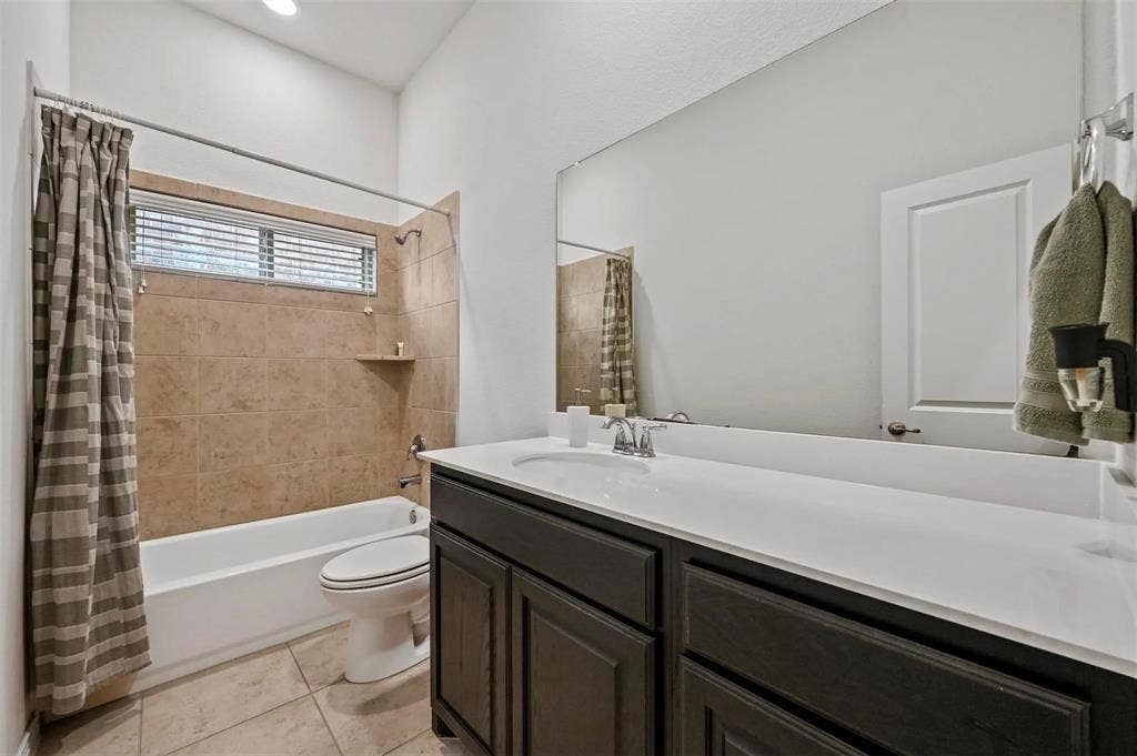 602 Brock Drive, Anna, TX 75409 Bathroom featuring a built-in tub with tile surround, a dark wood-finish vanity with an integrated sink, a large wall-mounted mirror, and tiled flooring