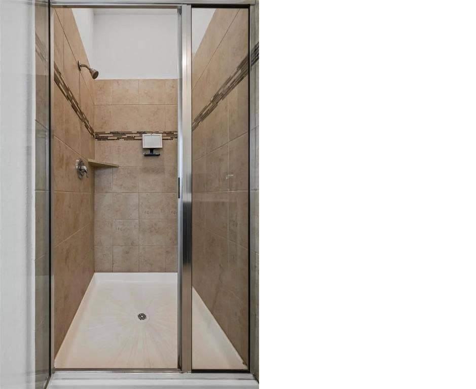 602 Brock Drive, Anna, TX 75409 Tiled shower with a mosaic accent band, built-in corner shelf, and glass enclosure