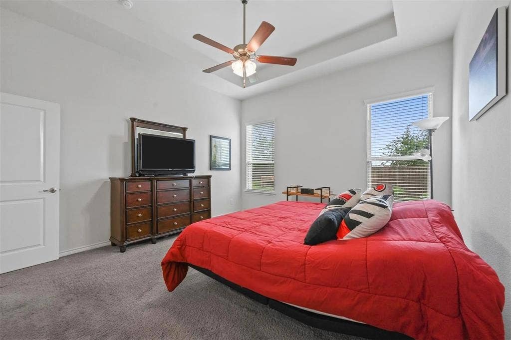 602 Brock Drive, Anna, TX 75409 Tray ceiling with a ceiling fan, two windows with blinds, and neutral carpeting