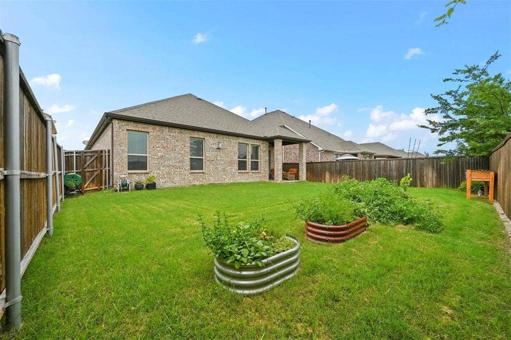 602 Brock Drive, Anna, TX 75409 Expansive backyard featuring a manicured lawn, full privacy fencing, and raised garden beds