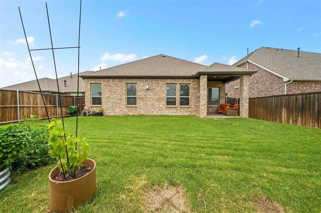 602 Brock Drive, Anna, TX 75409 Expansive backyard with a manicured lawn, full brick exterior, covered patio, and privacy fencing