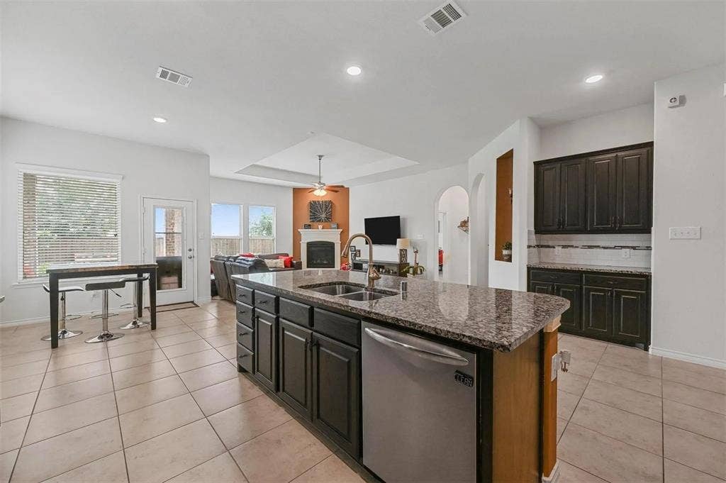 602 Brock Drive, Anna, TX 75409 Kitchen with tile flooring, island with integrated sink, stainless steel dishwasher, and granite-style countertop
