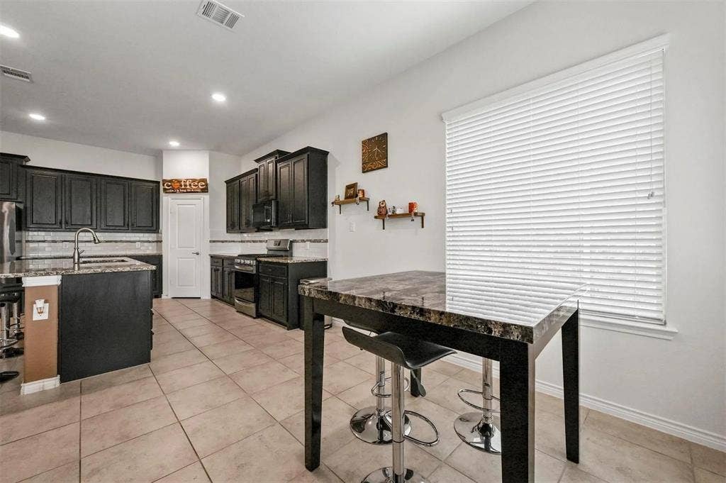 602 Brock Drive, Anna, TX 75409 Kitchen featuring dark wood cabinetry, stainless steel appliances, a tile backsplash, and stone-finish countertops
