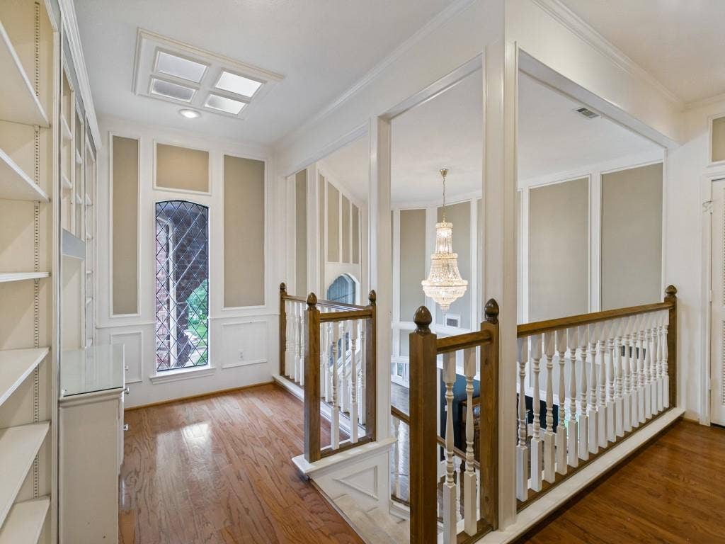 3309 Wolfe Court, Plano, TX 75025 Wood-finish flooring, built-in shelving, decorative wall paneling, stained glass window, and a white baluster railing with wood-finish handrail