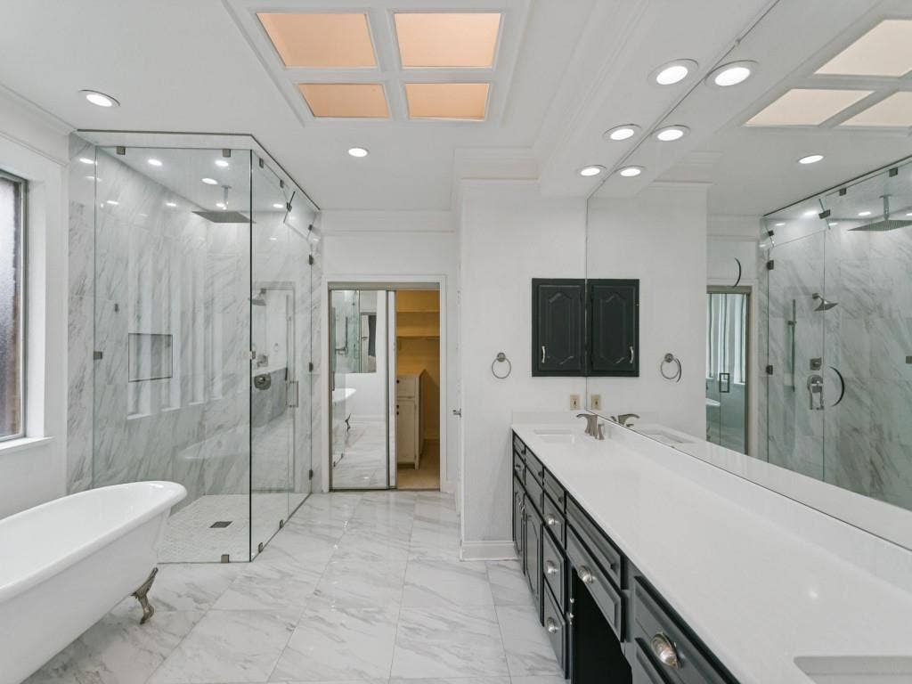 3309 Wolfe Court, Plano, TX 75025 White marble-finish tiled flooring, freestanding clawfoot bathtub, expansive glass-enclosed shower with multiple showerheads, dual vanity with undermount sinks, and recessed ceiling lighting