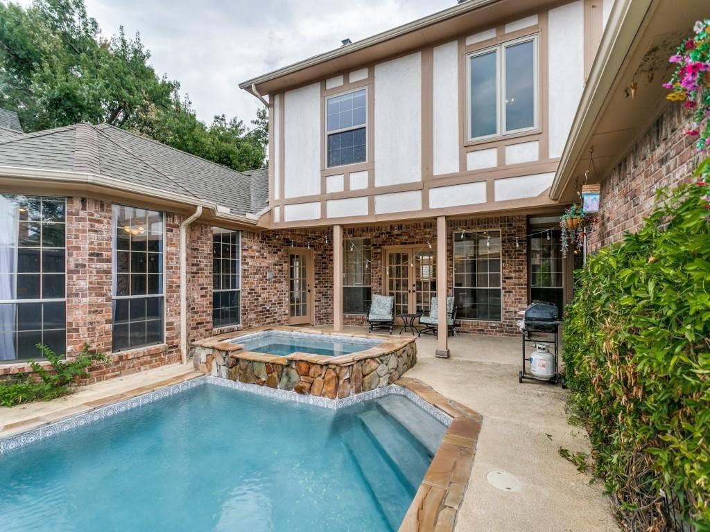 3309 Wolfe Court, Plano, TX 75025 Outdoor living area featuring a swimming pool, integrated spa with stone surround, and a covered patio with brick columns