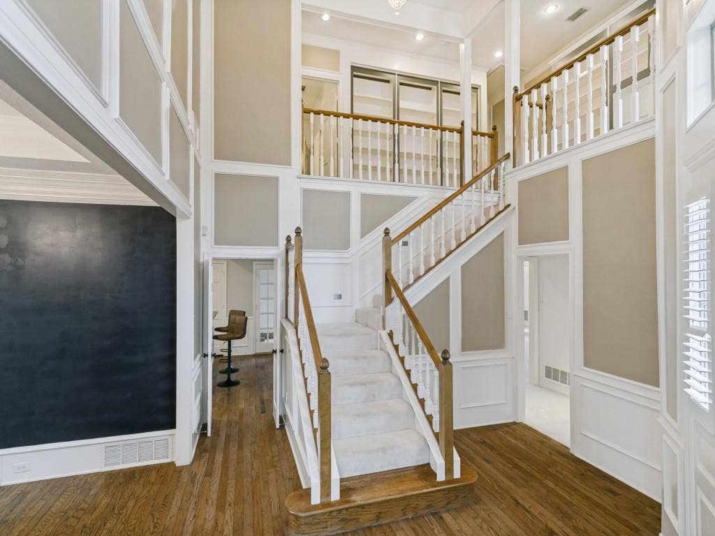 3309 Wolfe Court, Plano, TX 75025 Two-story entry featuring hardwood flooring, a grand staircase with carpeted treads, and extensive wainscoting
