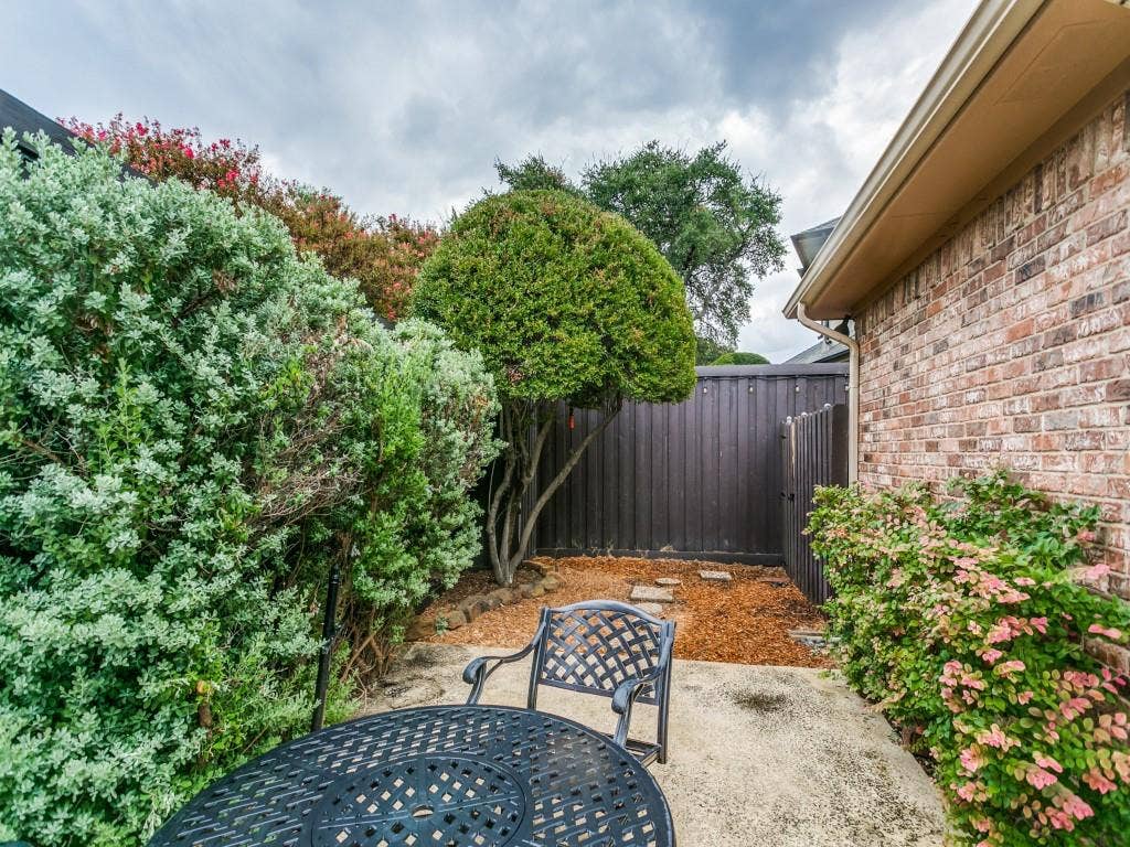 3309 Wolfe Court, Plano, TX 75025 Private patio area with concrete slab, brick exterior, wood fence, and mature landscaping