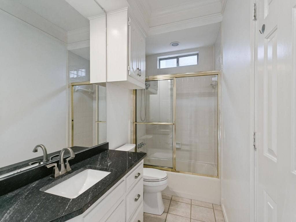 3309 Wolfe Court, Plano, TX 75025 Vanity with dark countertop and undermount sink, brushed nickel faucet, built-in upper cabinetry, white paneled door, and tiled flooring