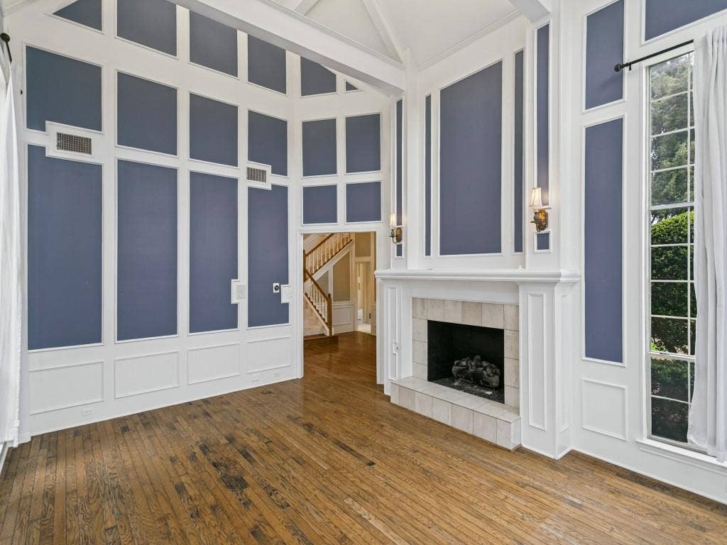 3309 Wolfe Court, Plano, TX 75025 Vaulted ceiling with exposed beams, hardwood flooring, fireplace with tile surround, tall windows, and decorative wall paneling