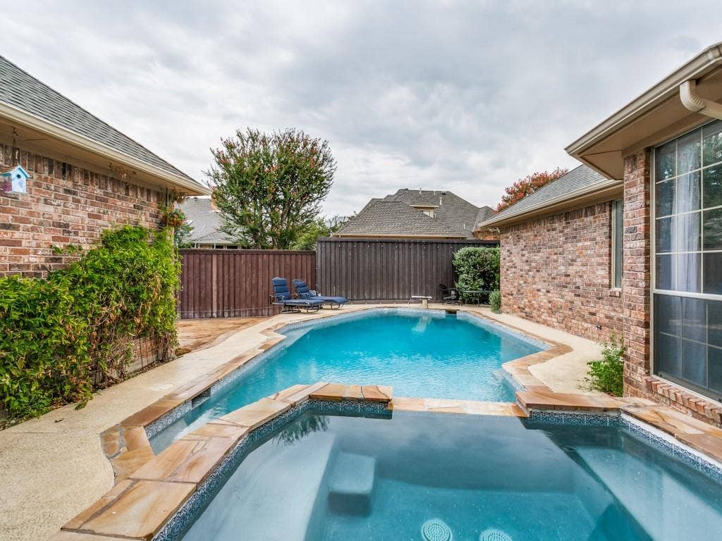 3309 Wolfe Court, Plano, TX 75025 Brick exterior featuring a swimming pool, integrated spa, and surrounding hardscaping