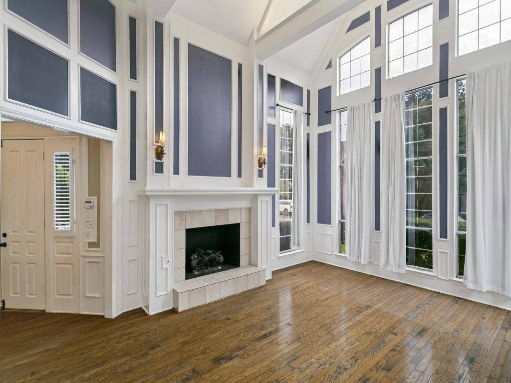 3309 Wolfe Court, Plano, TX 75025 Soaring vaulted ceiling with decorative wall paneling, a fireplace featuring a tile surround and hearth, and extensive windows