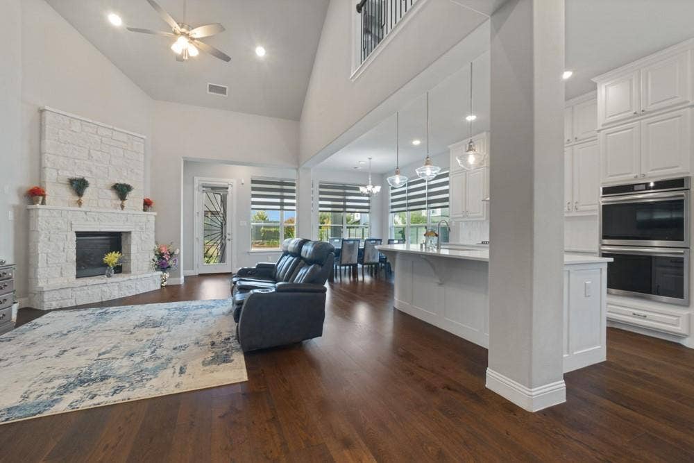 Hardwood-finish flooring, vaulted ceiling, stone-clad fireplace, integrated double oven, and white cabinetry
