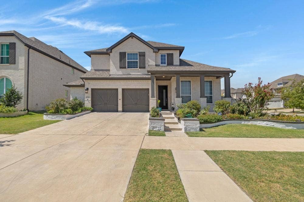 Two-story residence featuring a covered entry, columned porch, and a two-car garage