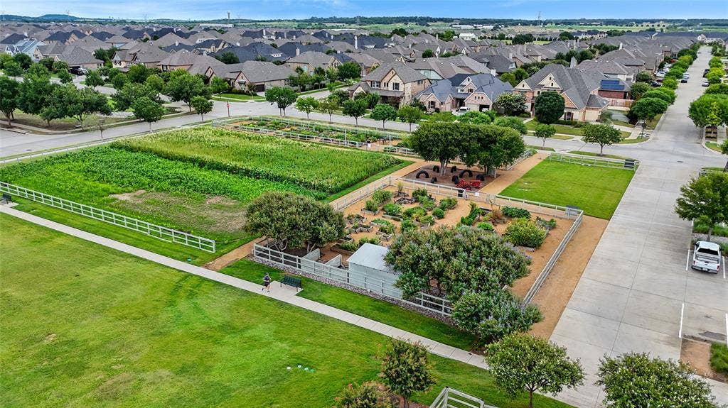 Expansive green space featuring a large community garden, walking paths, and mature trees