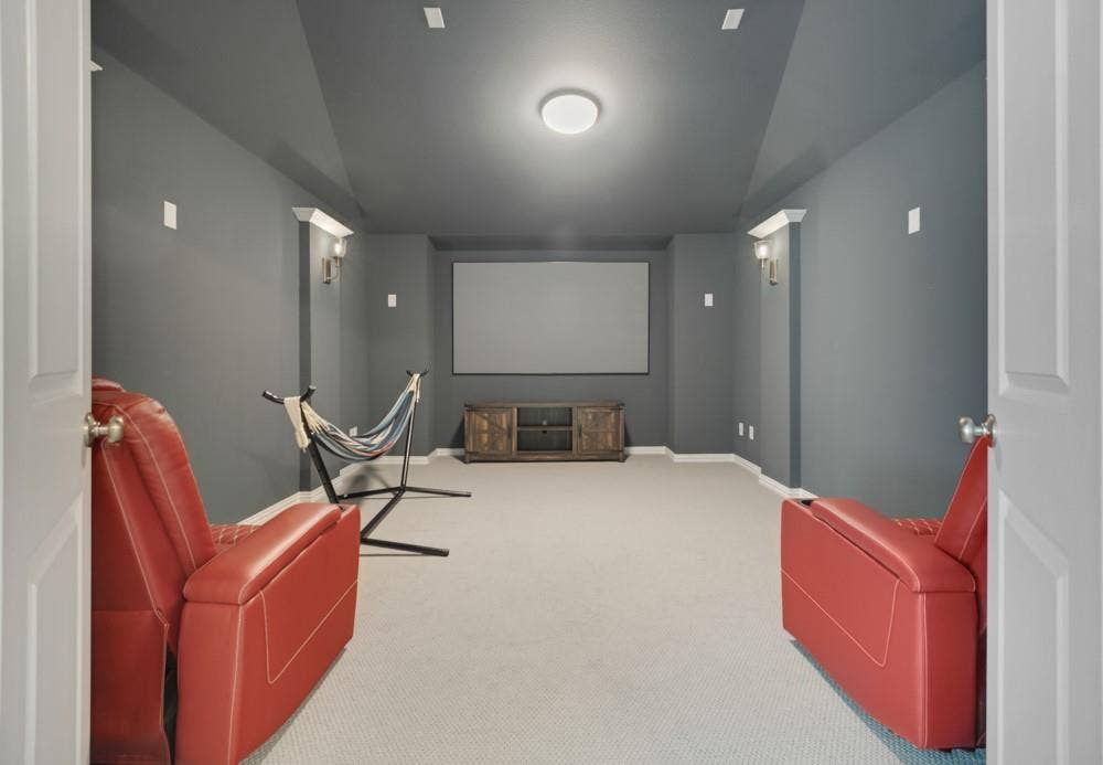 Recessed ceiling lighting, wall sconces, a projection screen, and light-colored carpeting complement the neutral wall tones
