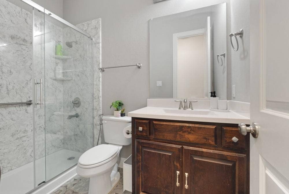Glass-enclosed shower with stone-finish surround and built-in shelving