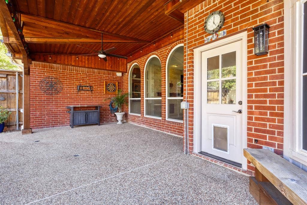 Covered patio featuring a wood-plank ceiling, exposed brick wall, arched windows, and concrete aggregate flooring