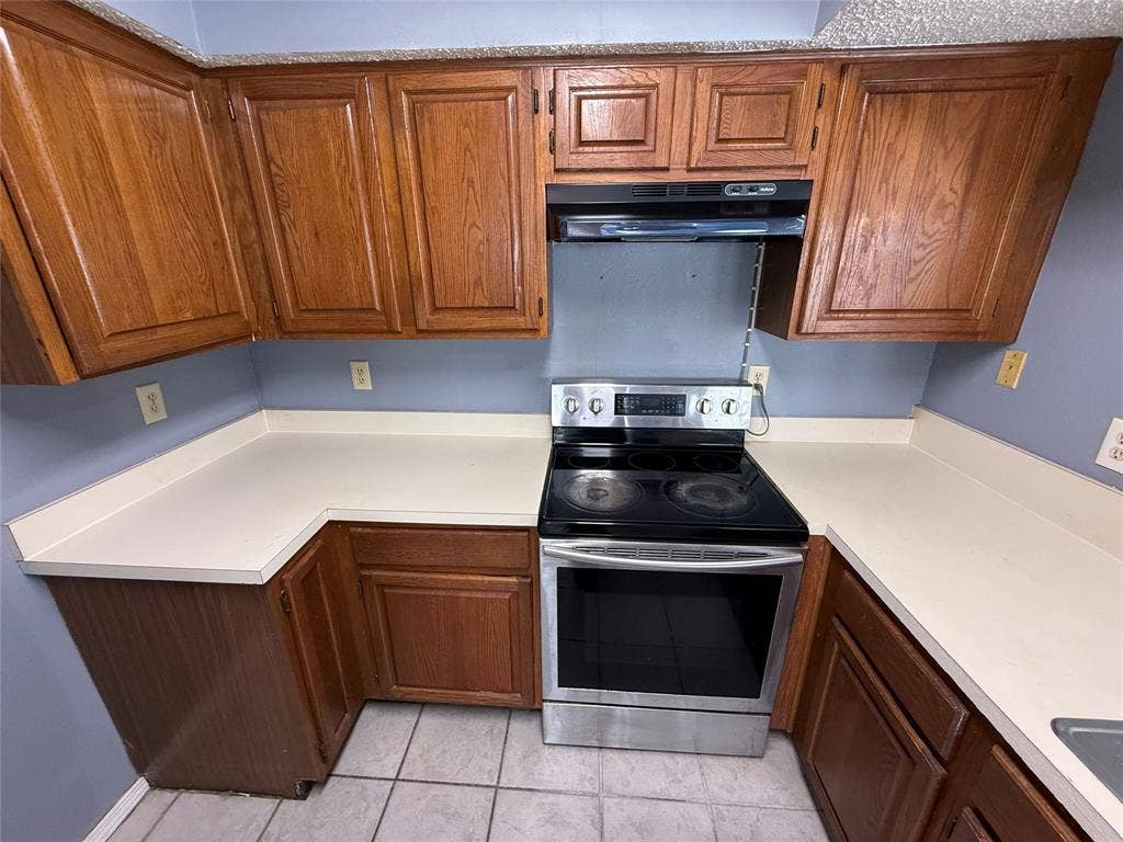 3402 Country Club Drive W, #154, Irving, TX 75038 Kitchen with wood-finish cabinetry, solid surface countertops, and a stainless steel electric range