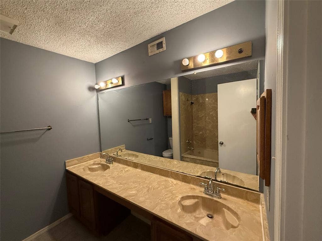 3402 Country Club Drive W, #154, Irving, TX 75038 Double vanity with integrated sinks, expansive counter space, wood-finish cabinetry, and overhead lighting
