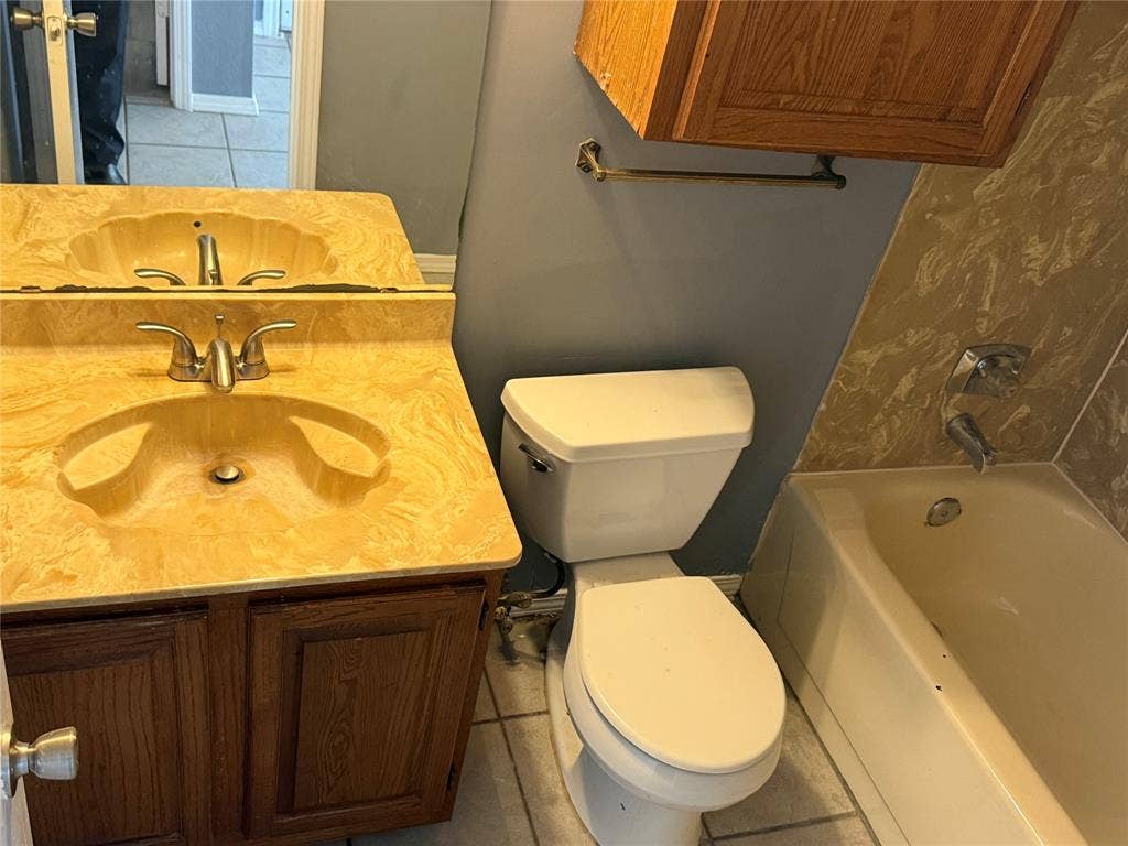3402 Country Club Drive W, #154, Irving, TX 75038 Vanity with integrated sink and wood-finish cabinetry, white toilet, and tub with wall-mounted faucet