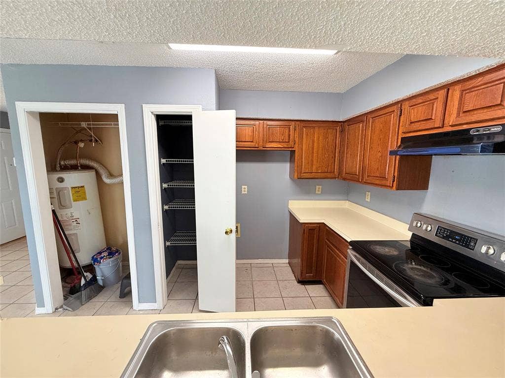 3402 Country Club Drive W, #154, Irving, TX 75038 Kitchen featuring wood cabinetry, solid surface countertops, and a stainless steel electric range