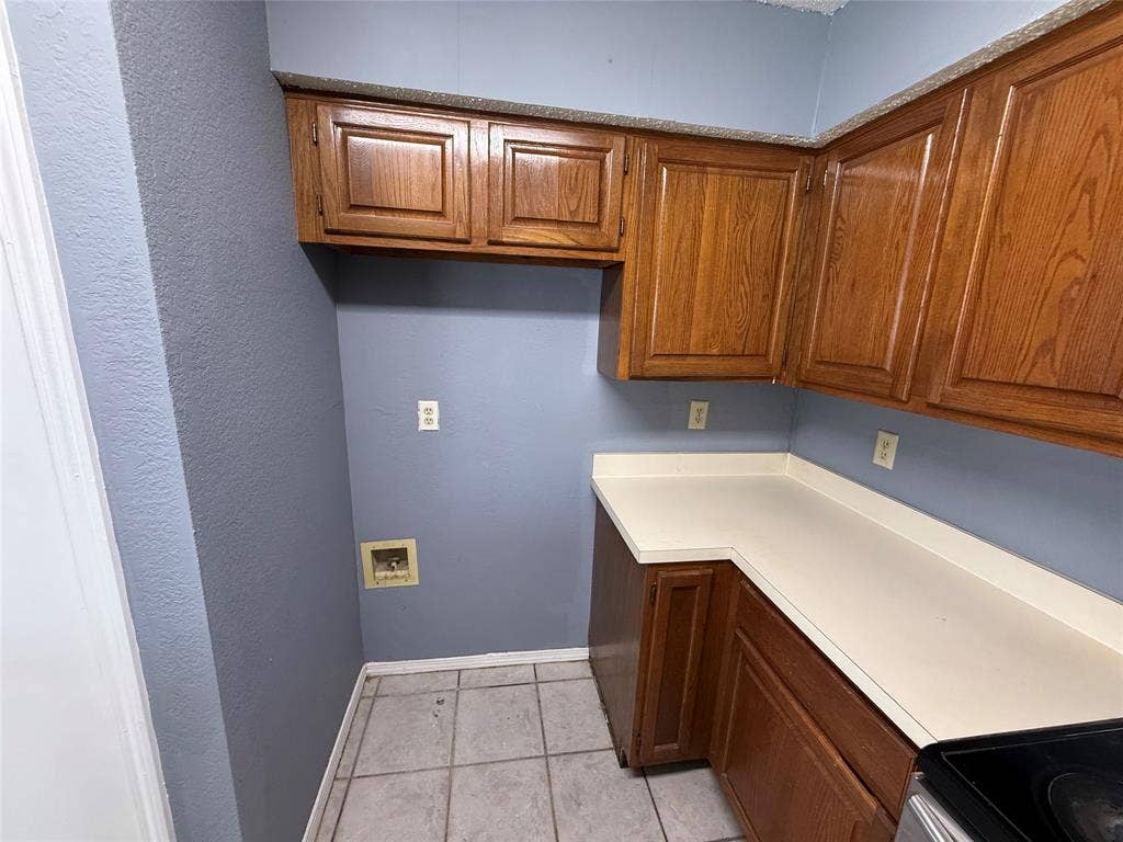3402 Country Club Drive W, #154, Irving, TX 75038 Wood-finish cabinetry with light-toned countertops, tiled flooring, and light blue walls