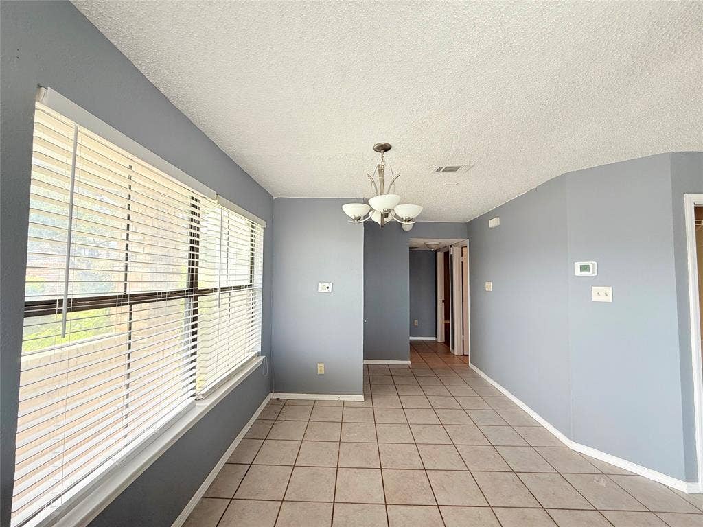 3402 Country Club Drive W, #154, Irving, TX 75038 Tiled flooring throughout, featuring a multi-light chandelier, and a large window with blinds