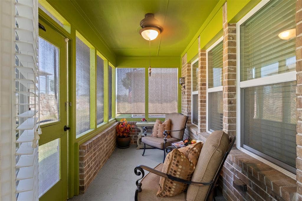 146 Montague Lane, Frisco, TX 75036 Screened porch featuring a brick half-wall, multiple windows with blinds, a ceiling-mounted light fixture, and a full-light exterior door