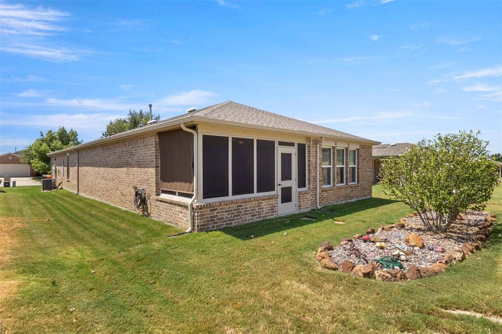 146 Montague Lane, Frisco, TX 75036 Brick exterior with a screened porch, multiple windows, and a landscaped garden bed