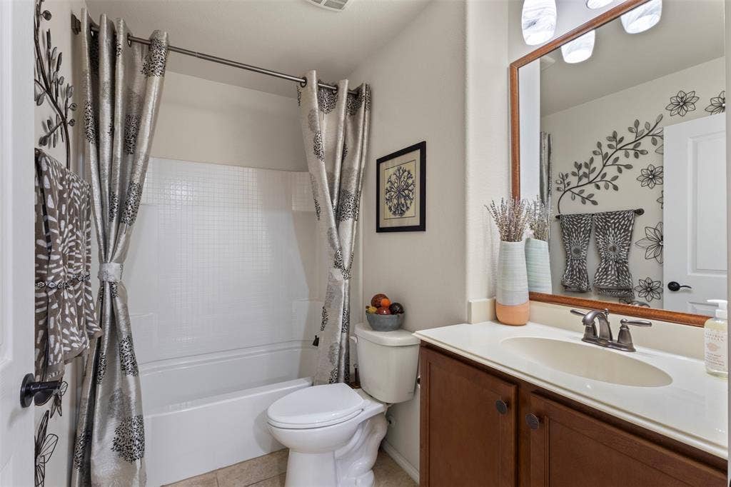 146 Montague Lane, Frisco, TX 75036 Bathroom featuring a full tub with shower, single vanity with integrated sink, wood-finish cabinetry, and a framed mirror with overhead lighting